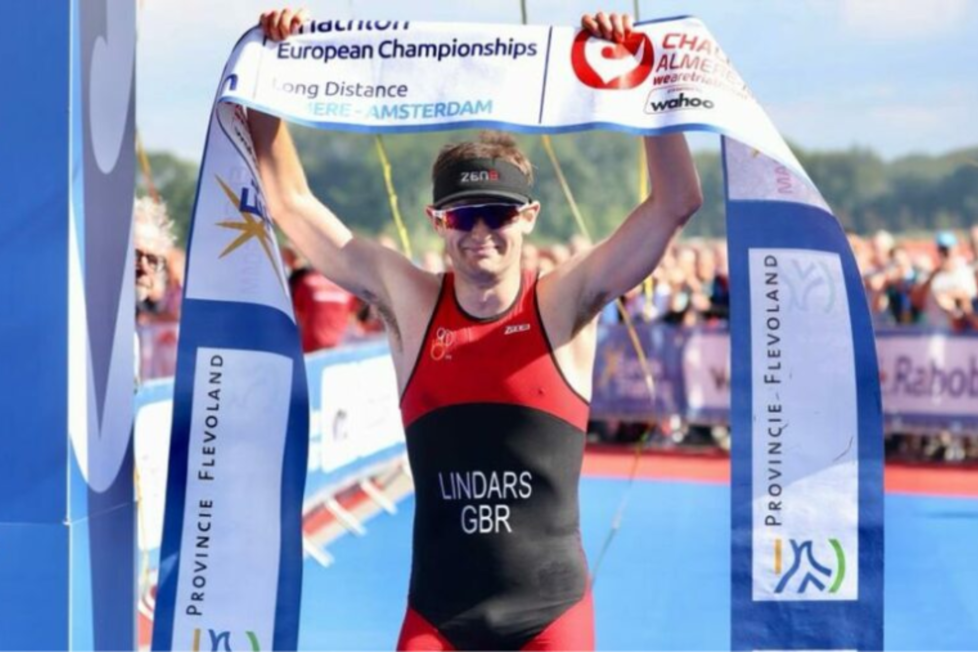 Kieran Lindars crossing the finish line at the Multisport European Championships in Amsterdam with both arms raised.