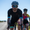 Man riding a road bike wearing the ZONE3 Activate+ men’s trisuit in black, with a white helmet and reflective sunglasses.