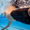 Underwater view of a swimmer in black MF-X jammer with a gold circular logo moving through the pool