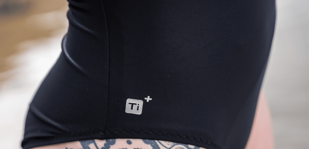 Close-up of a person wearing black TI+ thermal swimsuit with a logo on the leg.