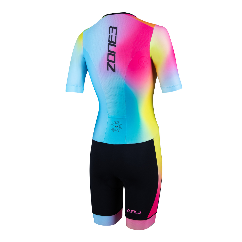 Back view of the ZONE3 Activate+ women's short sleeve trisuit with a vertical ZONE3 logo and colourful gradient across the upper body. Shorts are black with a small circular recycled label at the lower back.