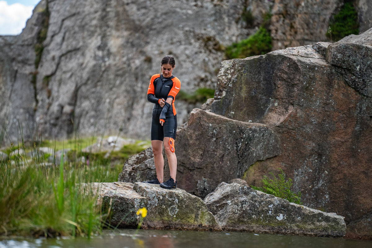 athlete putting on removable sleeves on the Zone3 Versa Swimrun in nature.