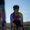 Woman cycling head-on wearing the ZONE3 Activate+ women’s short sleeve trisuit with mirrored sunglasses and a black helmet. Gradient design clearly shown across the chest and sleeves.