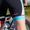 Cyclist wearing the ZONE3 trisuit. Close-up of the leg area shows the pink ZONE3 logo and gradient blue leg band next to a bicycle frame.