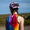 Cyclist wearing the ZONE3 Activate+ sleeveless trisuit with a pink helmet. The trisuit has a vertical ZONE3 logo and a bright gradient design on the back.