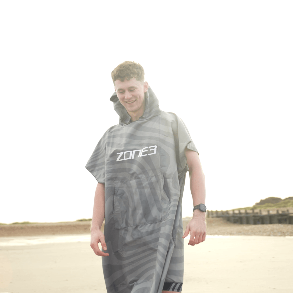 Man wearing a Microfibre Changing Robe on the beach, showcasing its lightweight and quick-drying features.