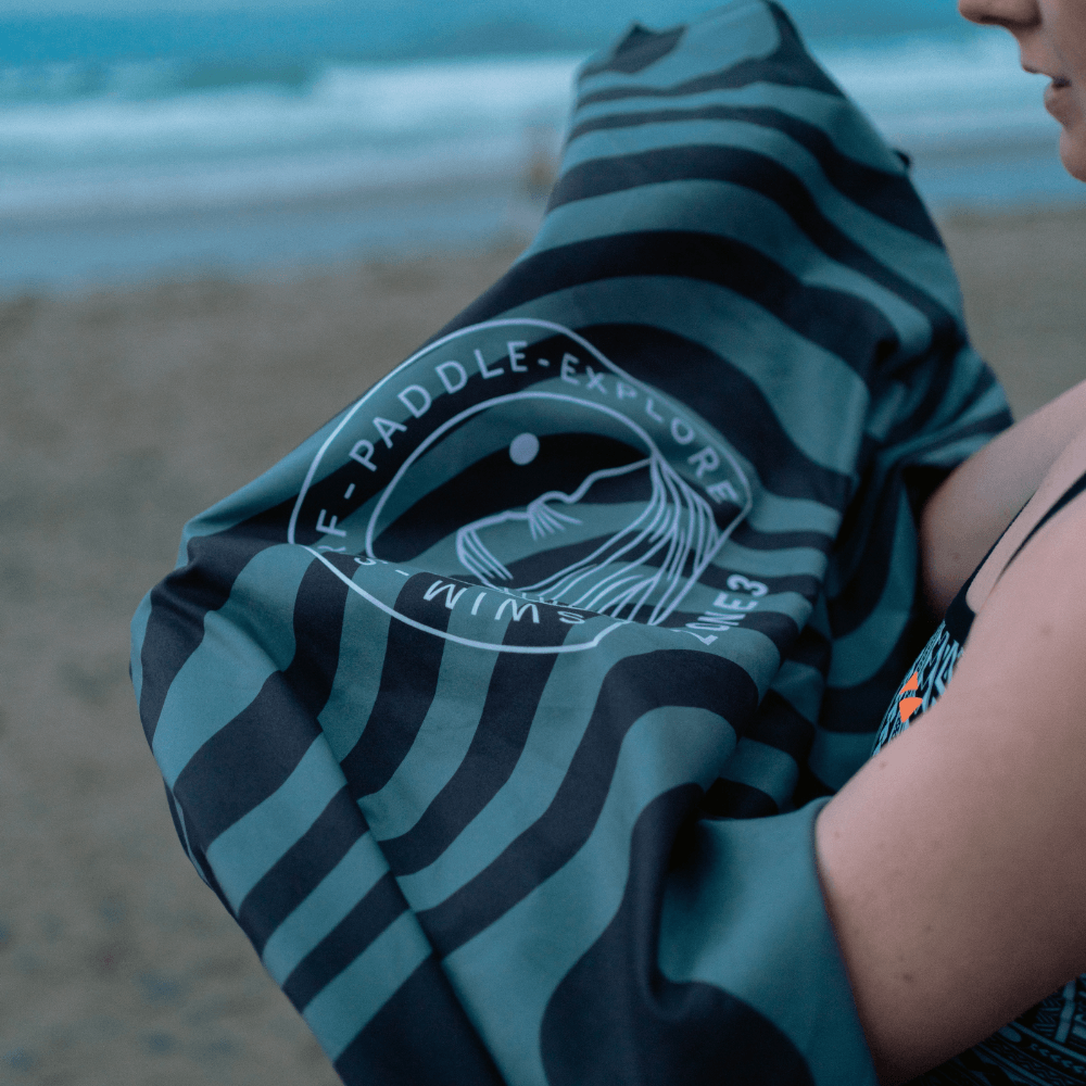 Microfibre Changing Robe being held on the beach, ideal for staying dry and comfortable during outdoor activities.