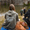 Person wearing a Microfibre Changing Robe by Zone3, relaxing by the water with a dog and swimmers in the background.